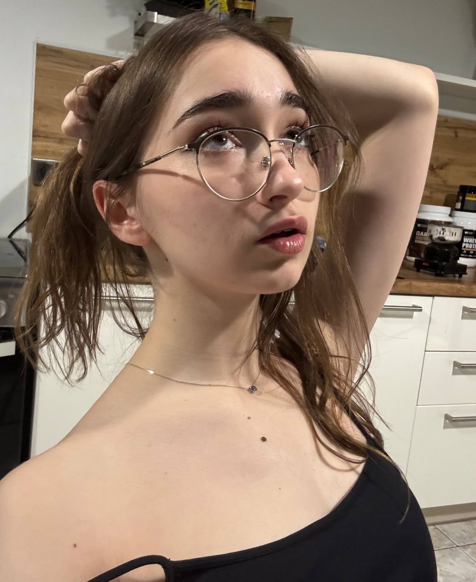 Thin teen with long hair takes selfies while wearing her glasses