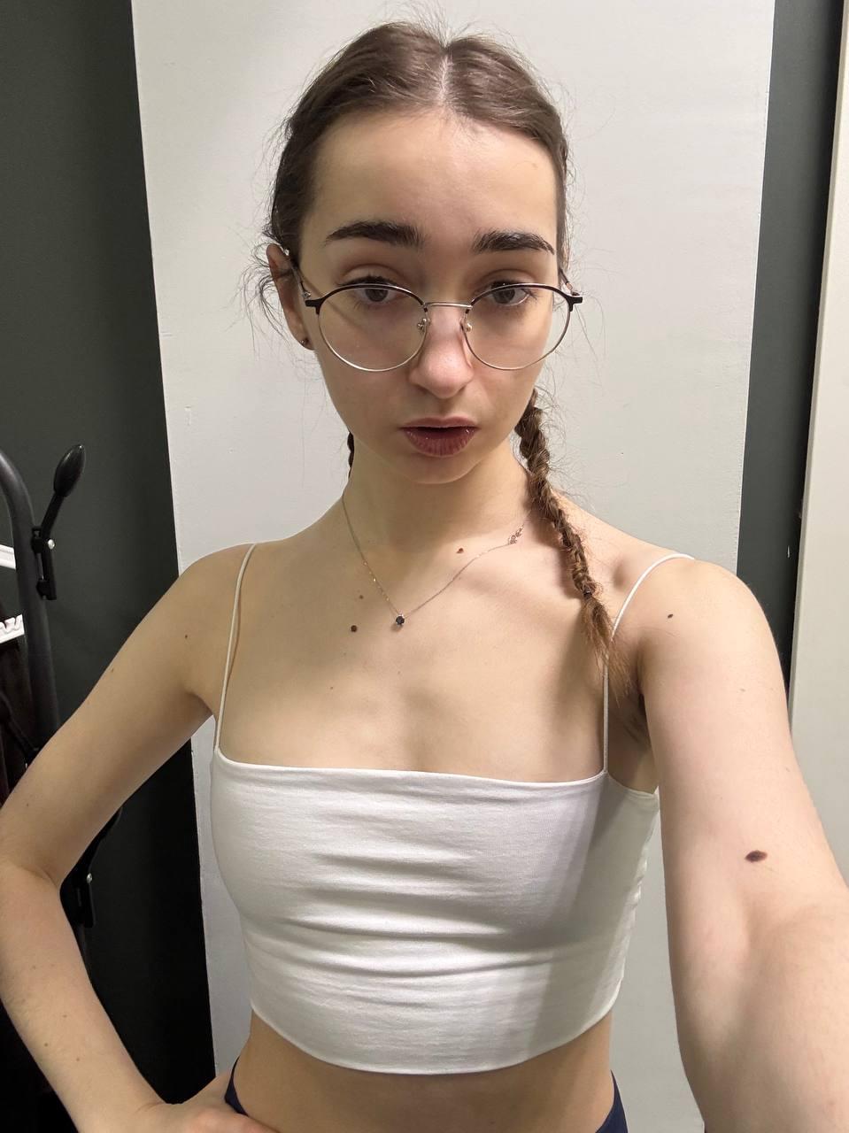 Thin teen with long hair takes selfies while wearing her glasses