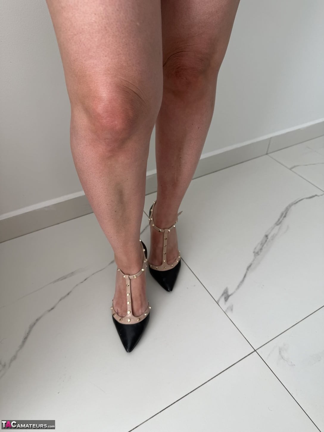 Tattooed older blonde unzips from a dress to get naked in high heels