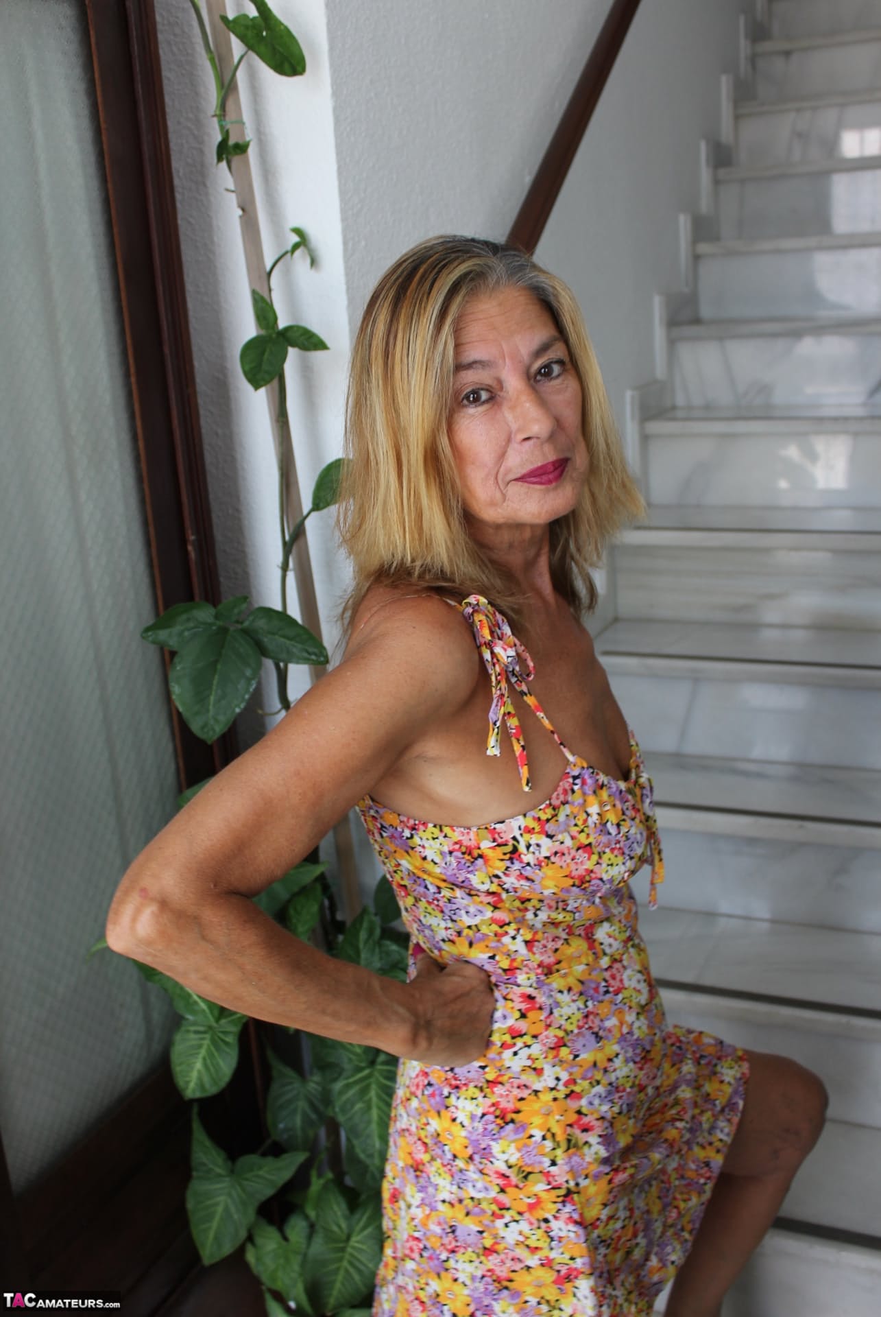 Mature blonde woman undoes buttons on her red dress before showing her tits