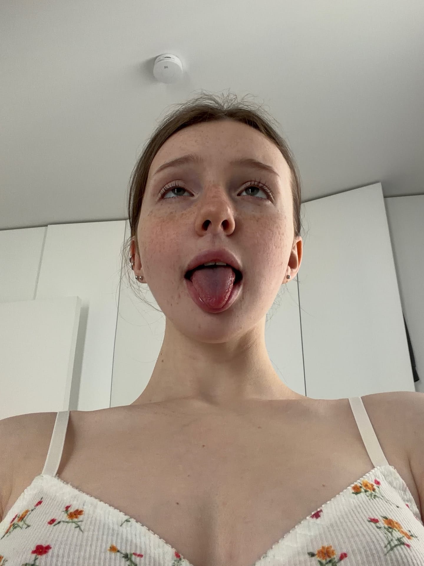 Skinny teen sticks out her tongue while getting undressed to pose nude