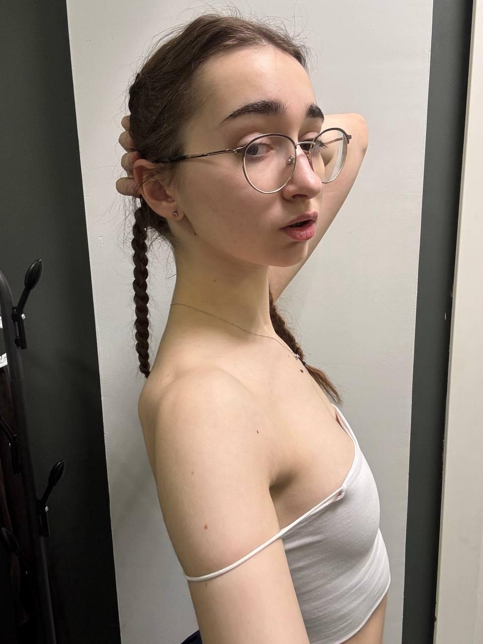 Thin teen with long hair takes selfies while wearing her glasses