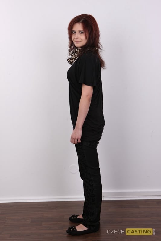 Solo girl with reddish hair stands straight and narrow while getting naked