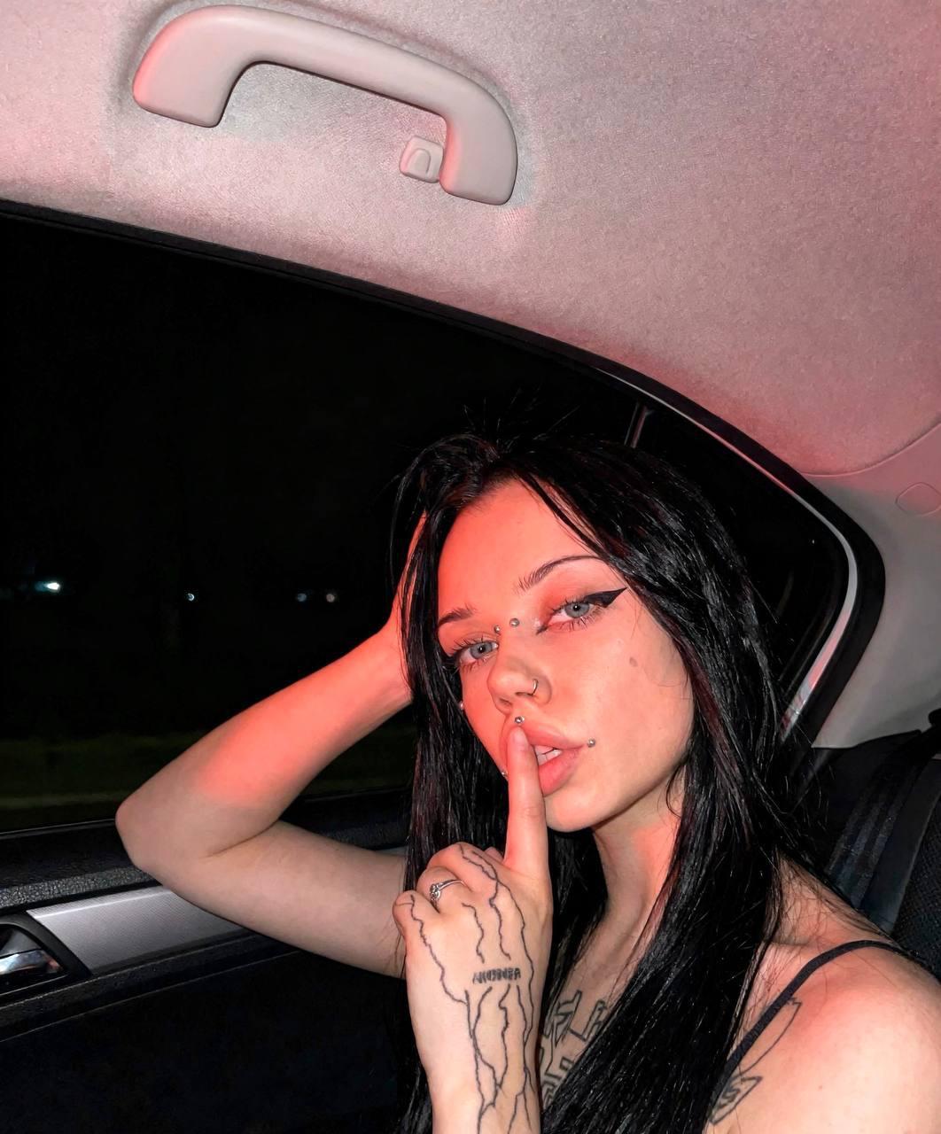 Dark-haired girl takes selfies while wearing black stockings and a black dress