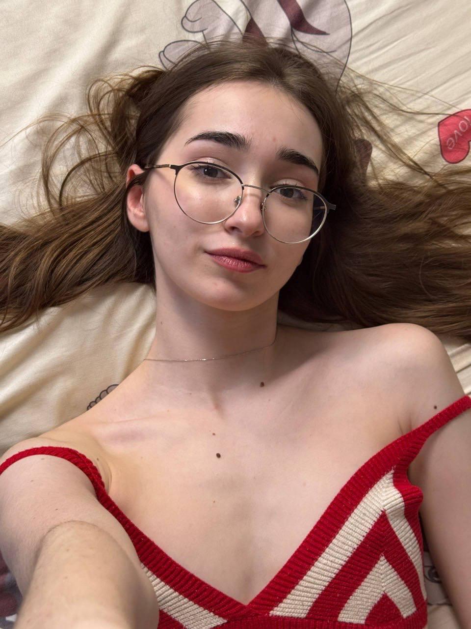 Amateur girl with glasses and long hair takes selfies in revealing outfits