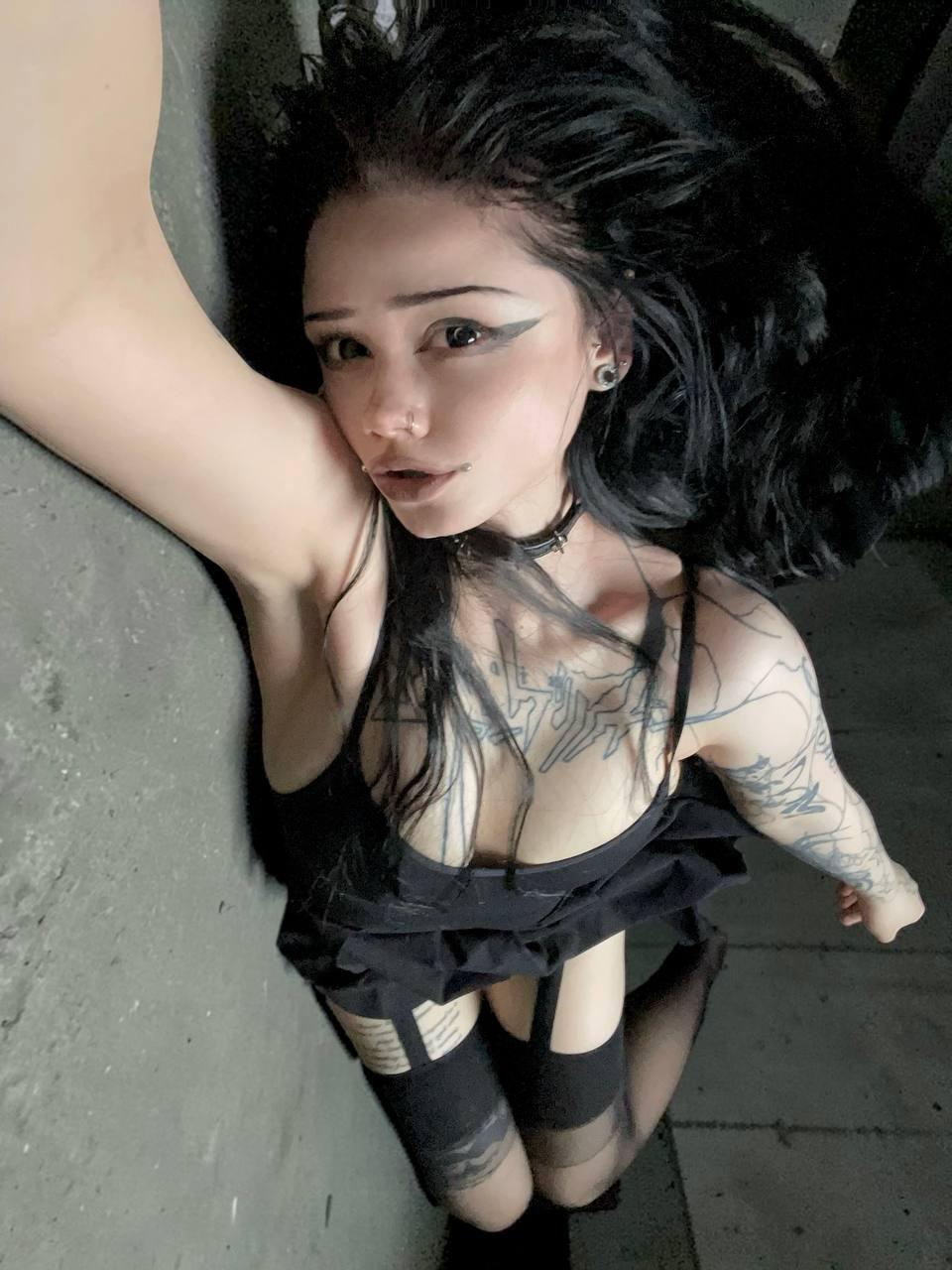 Dark-haired girl takes selfies while wearing black stockings and a black dress