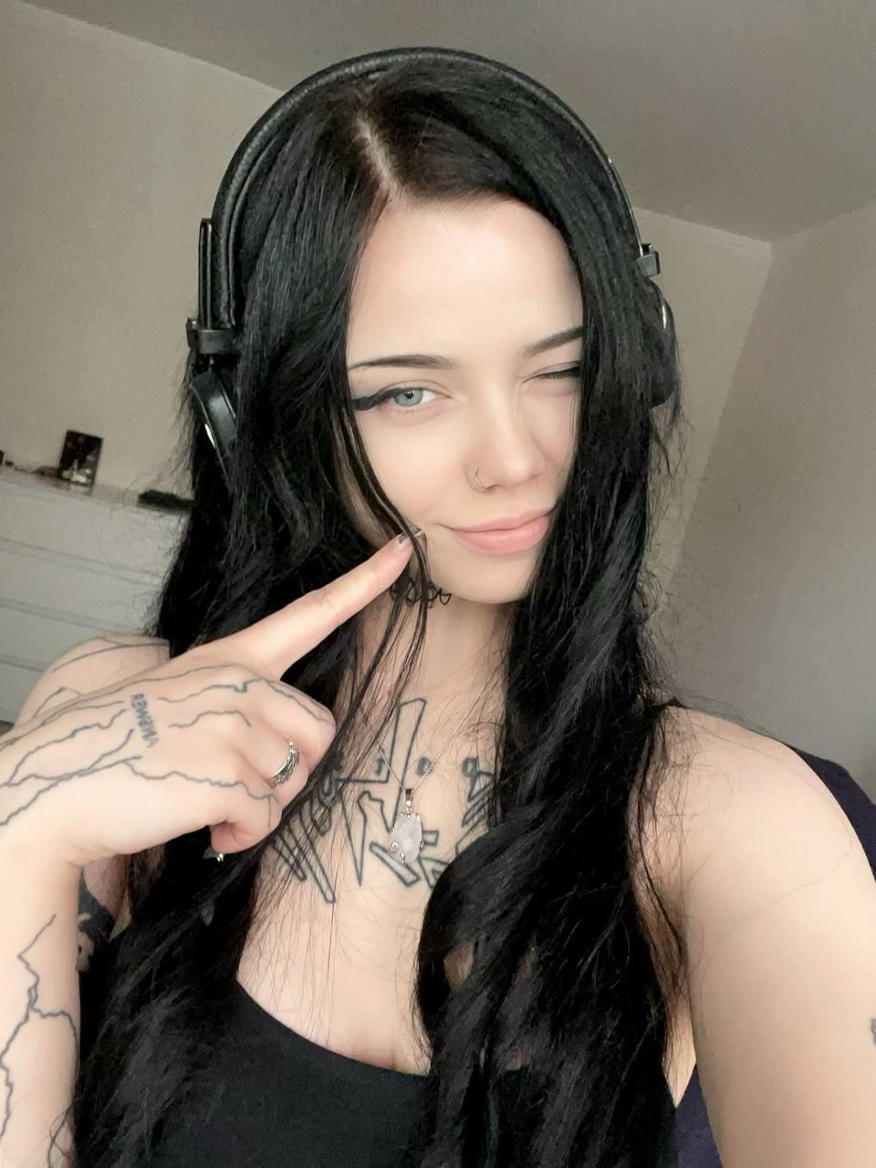 Dark-haired girl takes selfies while wearing black stockings and a black dress