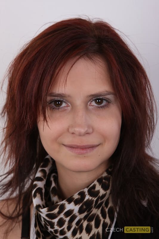 Solo girl with reddish hair stands straight and narrow while getting naked