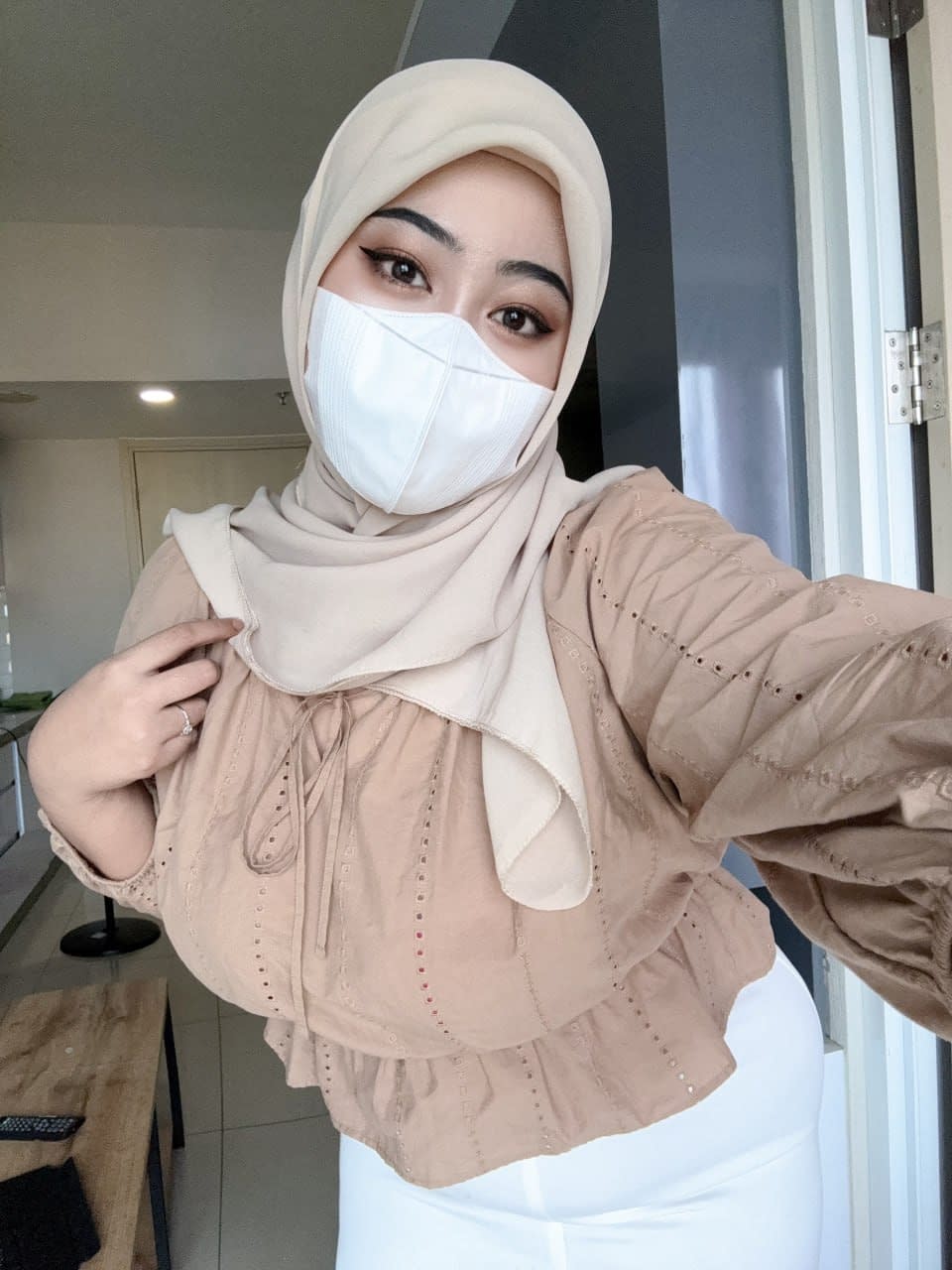 Solo girl with a mask over her mouth sports a hijab while exposing herself