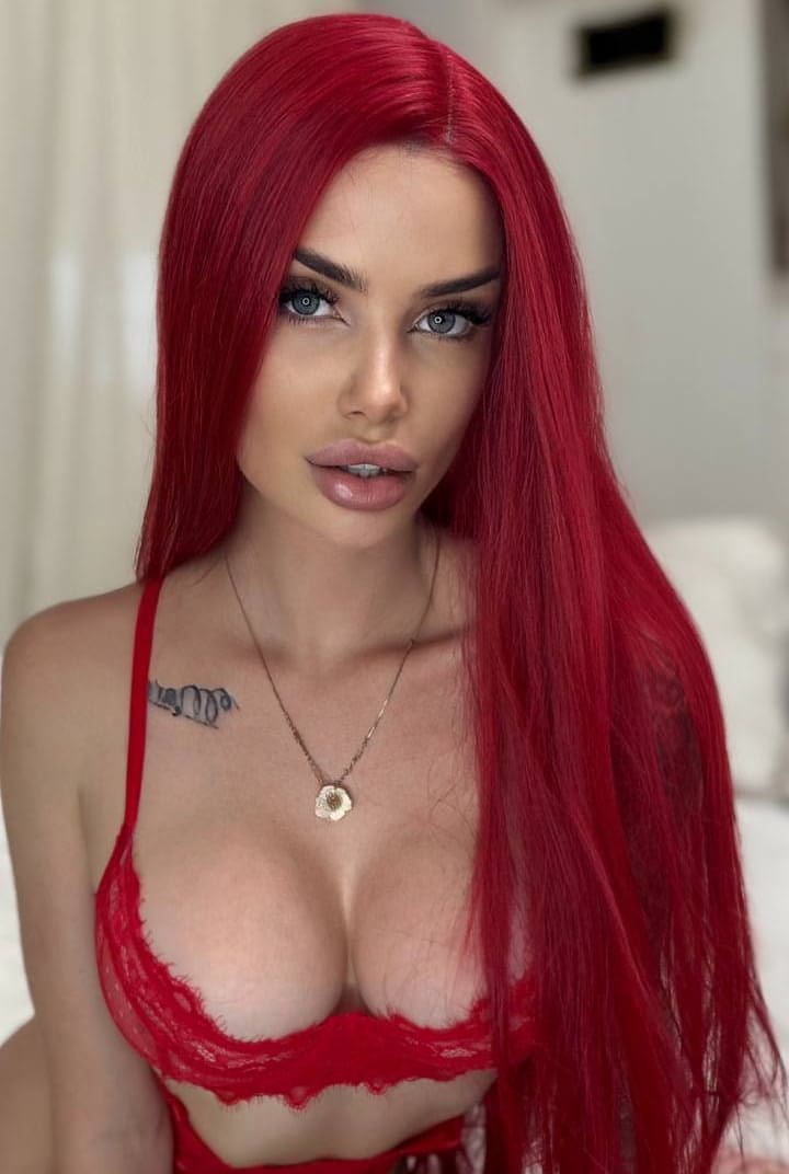 Gorgeous redhead with tattoos on her legs poses in red lace lingerie