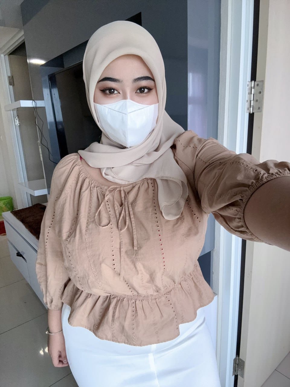 Solo girl with a mask over her mouth sports a hijab while exposing herself