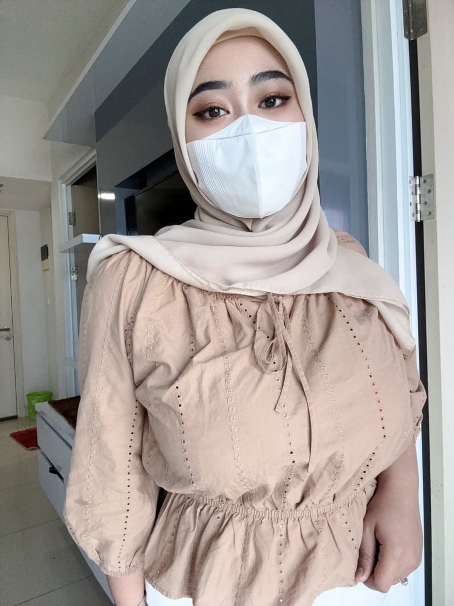 Solo girl with a mask over her mouth sports a hijab while exposing herself